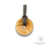 Natural 40mm agate donut pendant hanging from a black vegan cord.