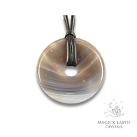 Natural 50mm agate donut pendant hanging from a black vegan cord.