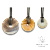 Natural agate donut pendants in three sizes hanging from black vegan cords arranged left to right from large to small
