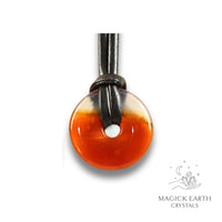 Natural 30mm carnelian donut pendant hanging from a black vegan cord.