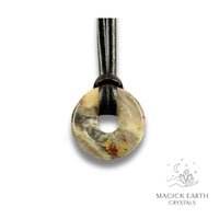 Natural 30mm cream shade crazy agate donut pendant hanging from a black vegan cord.