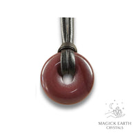 Natural 30mm darker shade mookaite jasper donut pendant hanging from a black vegan cord.
