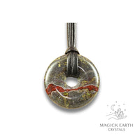 Natural 40mm dragons blood jasper donut pendant hanging from a black vegan cord.