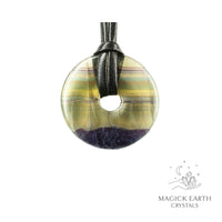 Natural 40mm fluorite donut pendant hanging from a black vegan cord.