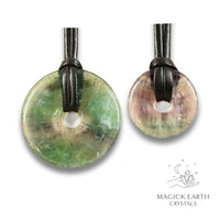 Natural light fluorite donut pendants in two sizes hanging from black vegan cords arranged left to right from large to small