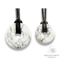 Natural howlite donut pendants in two sizes hanging from black vegan cords arranged left to right from large to small