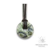 Natural 30mm kambaba jasper donut pendant hanging from a black vegan cord.