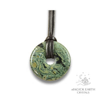 Natural 40mm kambaba jasper donut pendant hanging from a black vegan cord.