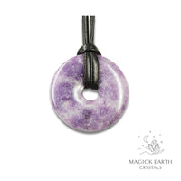 Natural 40mm lepidolite donut pendant hanging from a black vegan cord.