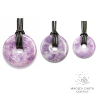 Natural lepidolite donut pendants in three sizes hanging from black vegan cords arranged left to right from large to small