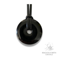 Natural 40mm obsidian donut pendant hanging from a black vegan cord.