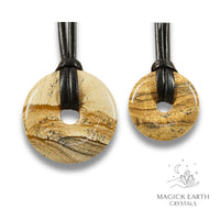 Natural picture jasper donut pendants in two sizes hanging from black vegan cords arranged left to right from large to small