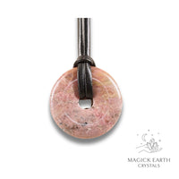 Natural 40mm lighter shade rhodonite donut pendant hanging from a black vegan cord.