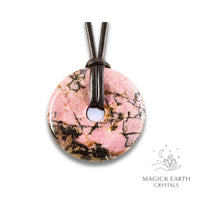 Natural 50mm darker shade rhodonite donut pendant hanging from a black vegan cord.