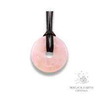 Natural 40mm rose quartz donut pendant hanging from a black vegan cord.