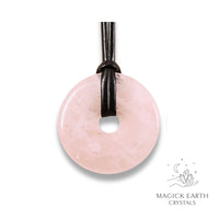 Natural 50mm rose quartz donut pendant hanging from a black vegan cord.