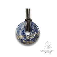 Natural 40mm sodalite donut pendant hanging from a black vegan cord.