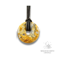 Natural 40mm yellow shade crazy agate donut pendant hanging from a black vegan cord.