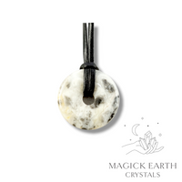 Natural 40mm cream shade crazy agate donut pendant hanging from a black vegan cord.
